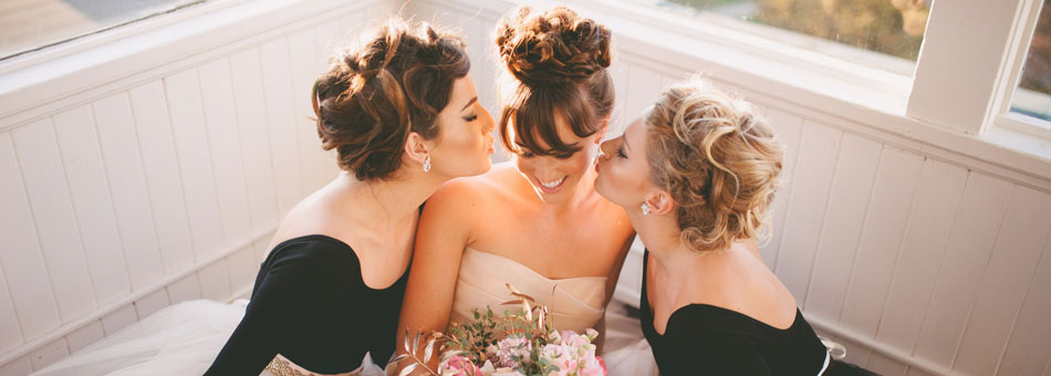 bride and bridesmaids kissing on cheek photography by ainsley rose